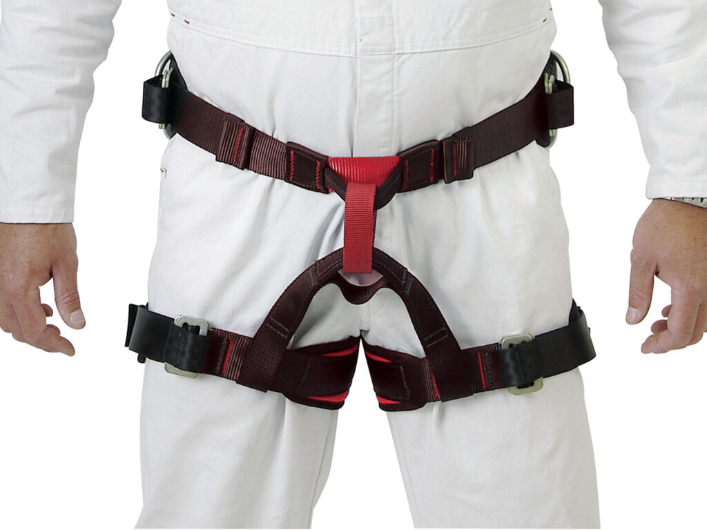 Torso view of Ferno Centrepoint sit harness. The harness is red and black and worn over white coveralls. Safety equipment for work at height.